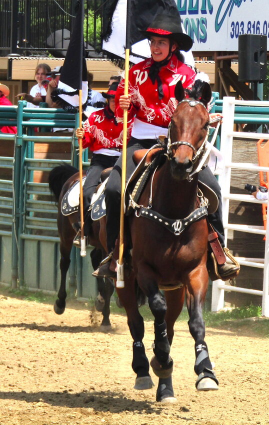 A rider brings an American flag into the rodeo grounds.